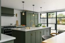 a chic contemporary kitchen with green cabinets, white countertops, a black cooker and bulbs over the kitchen island