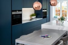 a chic contemporary navy kitchen with a white kitchen island and matching countertops plus a grey table for breakfasts