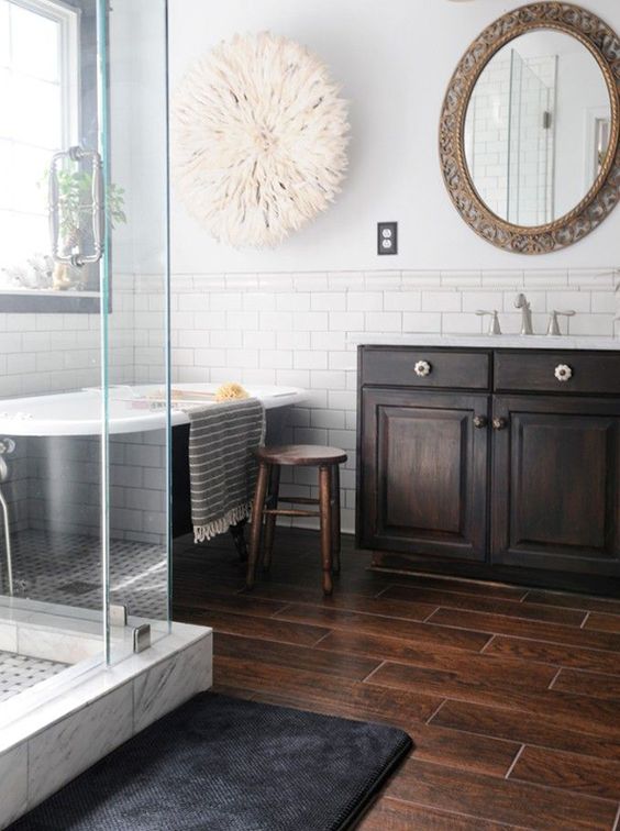 a chic contrasting bathroom with a dark wood tile floor, white subway tiles on the walls, a dark vanity, a shower and a tub