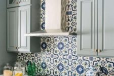 a chic grey kitchen with a bright blue and white mosaic tile backsplash and white countertops is bright and refined