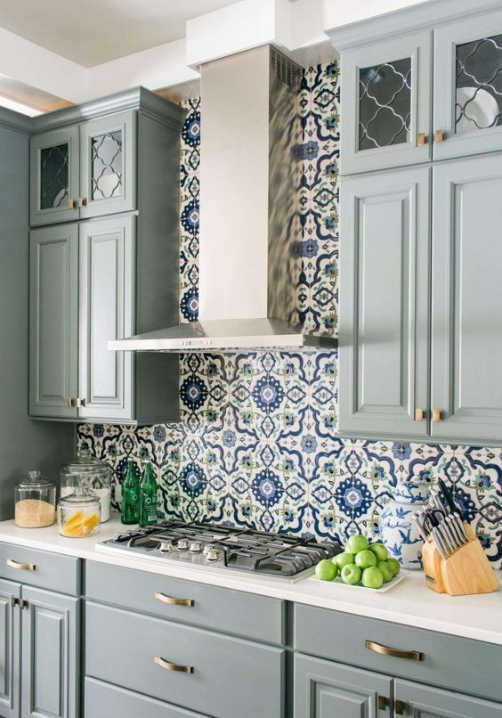 a chic grey kitchen with a bright blue and white mosaic tile backsplash and white countertops is bright and refined