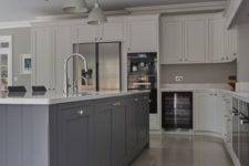 a chic kitchen with dove grey cabinets, a pale blue kitchen island, grey lamps and white stone countertops