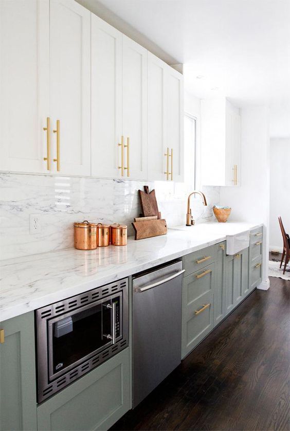 a chic kitchen with pale green and white cabinets, gold handles and white stone countertops and backsplashes for a fresh feel