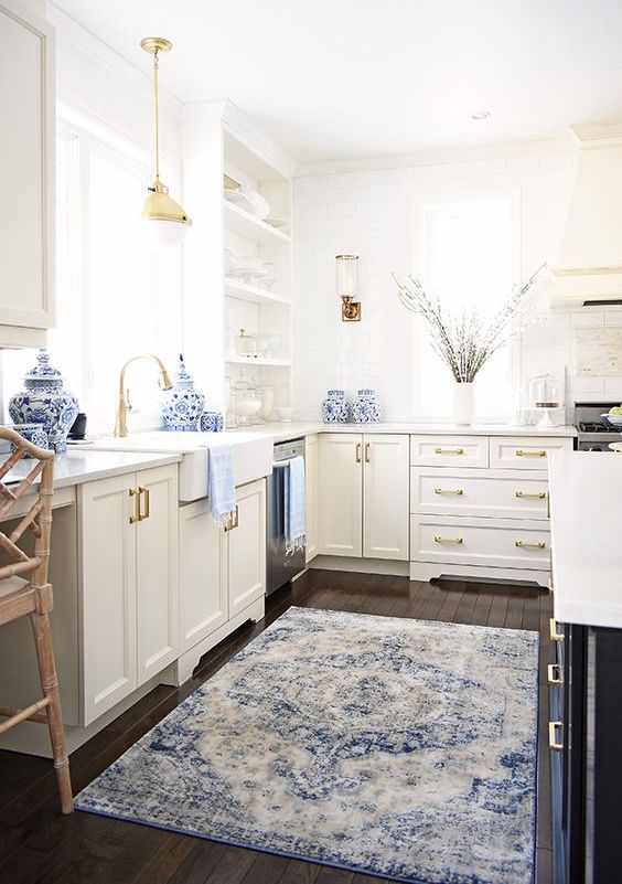 a chic neutral kitchen spruced up with a blue rug and some porcelain and touches of gold for more chic