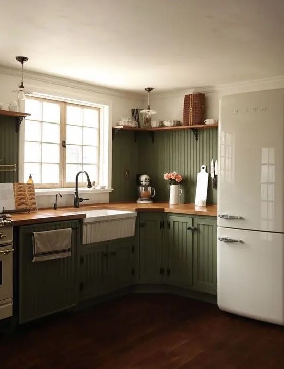 a chic olive green farmhouse kitchen with fluted cabinets, butcherblock countertops, black fixtures and open shelves is cool