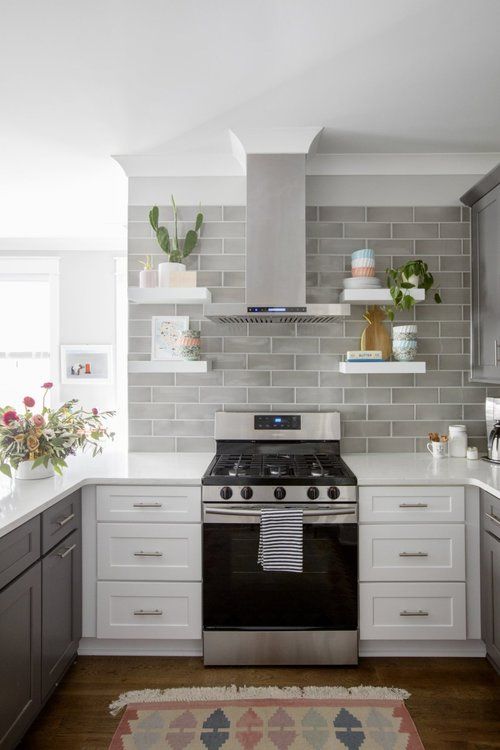 a chic two tone kitchen with grey and white cabinets, a grey tile backsplash and white countertops