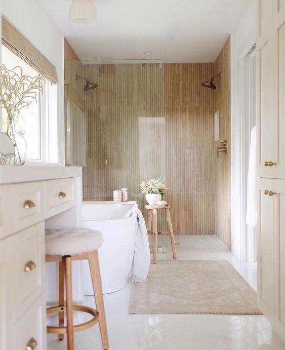 a contemporary bathroom with wood look tiles, an oval bathtub, a white vanity and a neutral stool