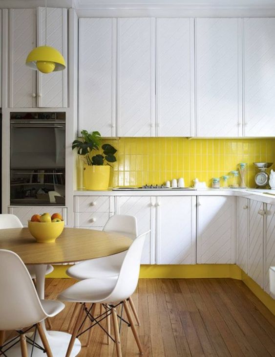 a contemporary kitchen done in lemon yellow and white, with textural cabinets and a wooden floor looks bold