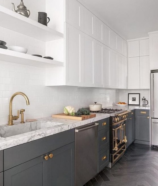 a contemporary kitchen with lower grey cabinets, white upper ones, gold and brass touches, white countertops