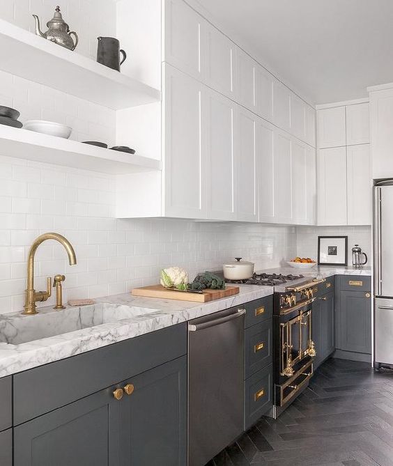 a contemporary kitchen with lower grey cabinets, white upper ones, gold and brass touches, white countertops