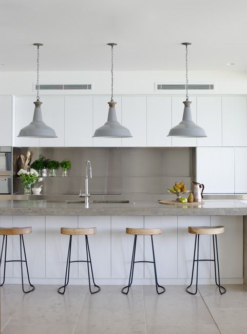 a contemporary kitchen with sleek white cabinets, a grey backsplash, a kitchen island with a grey countertop and grey pendant lamps