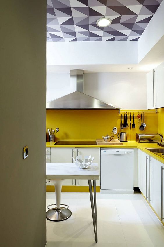 a contemporary white kitchen made bold with a yellow backsplash and countertops plus staineless stele appliances