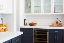 a contrasting kitchen with navy lower cabinets, white upper ones, white tile backsplashes and white countertops