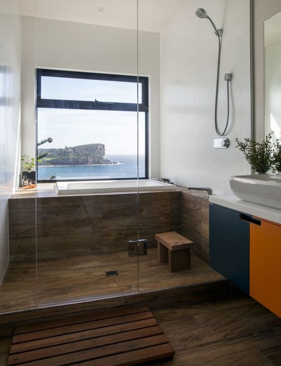 a cool bathroom clad with wood tiles, with a color block vanity and a gorgeous view that creates a mood