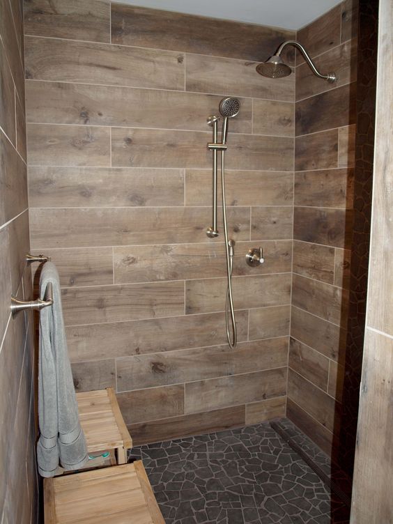 a cool shower space with wood-look tiles, a black floor, a wooden bench is a chic and cozy space to have a wash