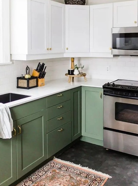 a cool two-tone kitchen with white and olive green shaker cabinets, white stone countertops and a white subway tile backsplash and gold knobs