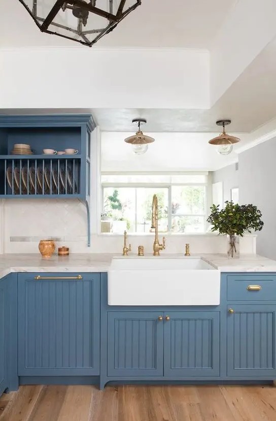 a dapper kitchen in blue refreshed with white stone countertops and a white tile backsplash plus gold