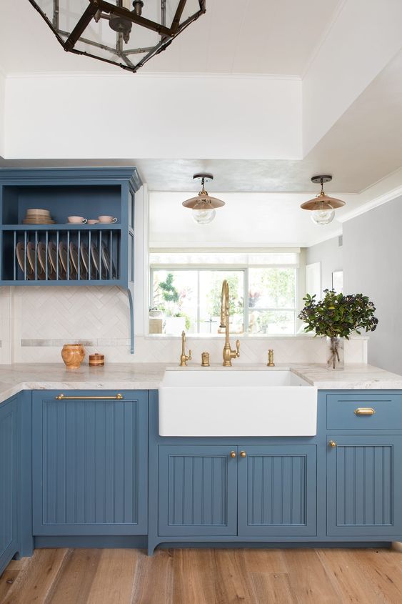 a dapper kitchen in blue refreshed with white stone countertops and a white tile backsplash plus gold