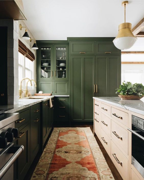 a dark green kitchen, a light colored wood kitchen island, white stone countertops and gold touches for a mid-century modern feel