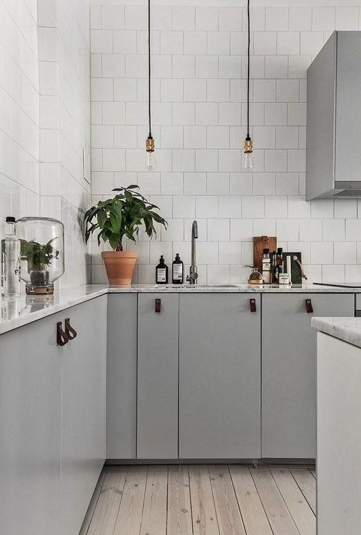 a gorgeous Scandinavian kitchen with grey cabinets, white marble countertops and white square tiles is very elegant