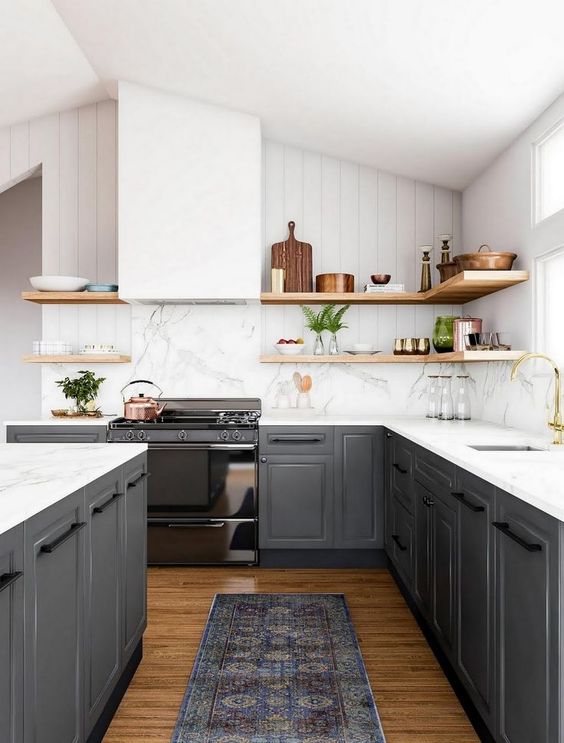 a gorgeous contrasting kitchen with graphite grey cabinets, white countertops and a backsplash, a hood, wooden shelves for a softer look