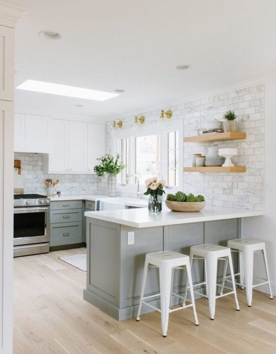 a grey and white kitchen with shaker cabinets, white countertops, a white marble tile backsplasgh and white metal stools