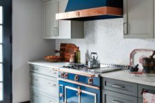 a grey art deco kitchen with a bright blue cooker and copper touches plus a mosaic tile backsplash looks wow