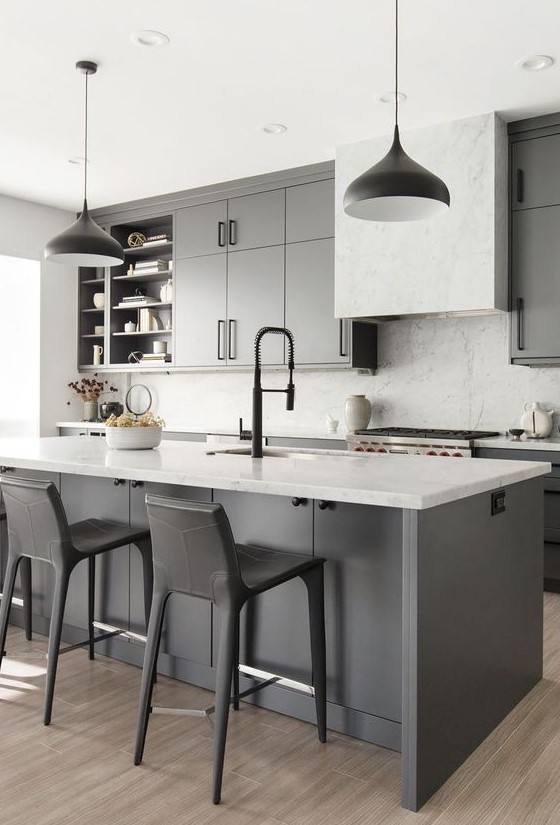 a grey farmhouse kitchen with white countertops, a white marble backsplash, black pendant lamps and black stools