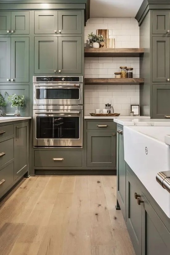 a large olive green farmhouse kitchen with shaker cabinets, white stone countertops, open shelves, a white subway tile backsplash