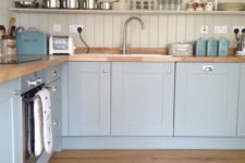 a light blue kitchen with a dove grey wall and beadboard backsplash plus wooden countertops to make the look warmer and softer