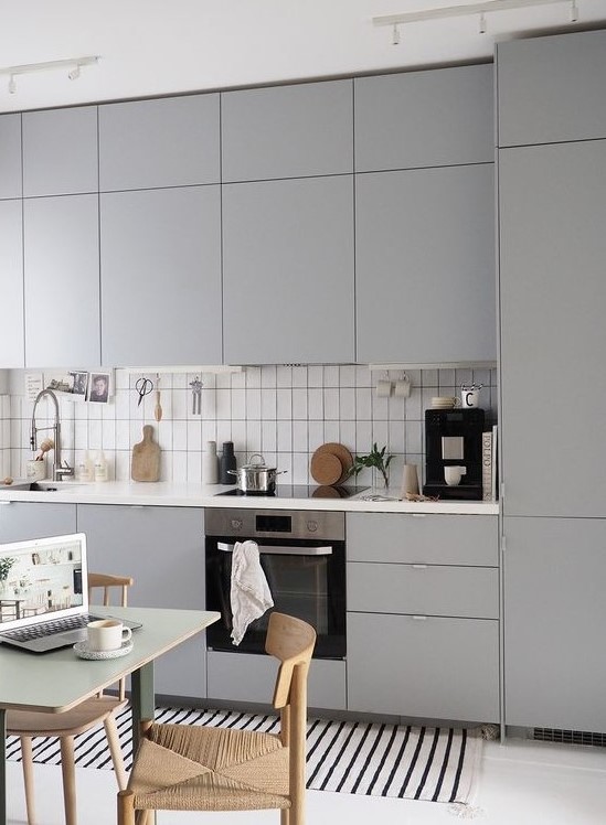 a lovely Nordic kitchen in grey, white skinny tiles, a striped rug, woven chairs is welcoming and very stylish