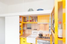 a mini contemporary kitchen done in sunny yellow and with natural wood touches plus built-ins is bold