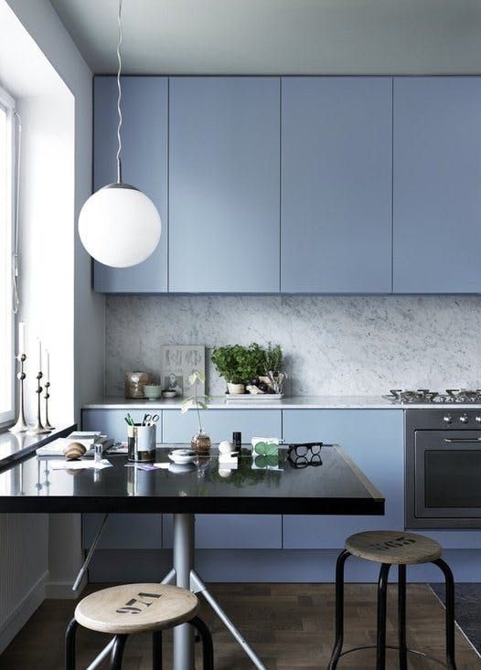 a minimalist light blue kitchen with a grey stone backsplash and countertops finished with industrial stools and a black table