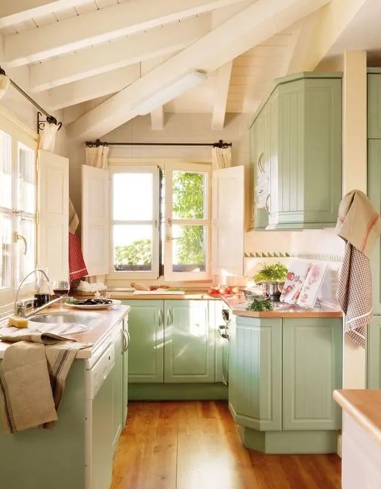 a mint farmhouse kitchen with beadboard cabinets, butcherblock countertops and lots of natural light