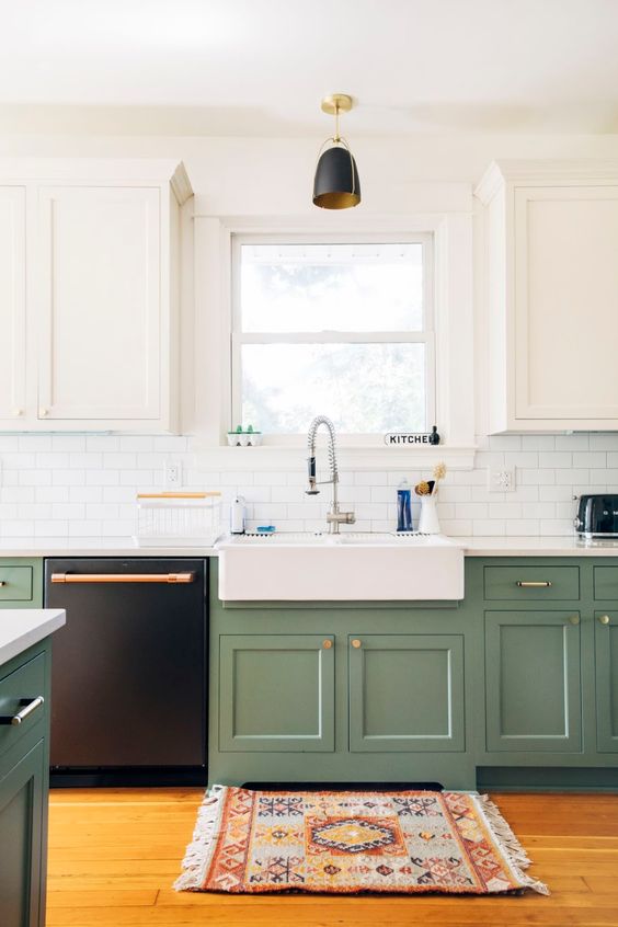 a modern kitchen with white and grene cabinets, touches of gold and copper and a boho printed rug