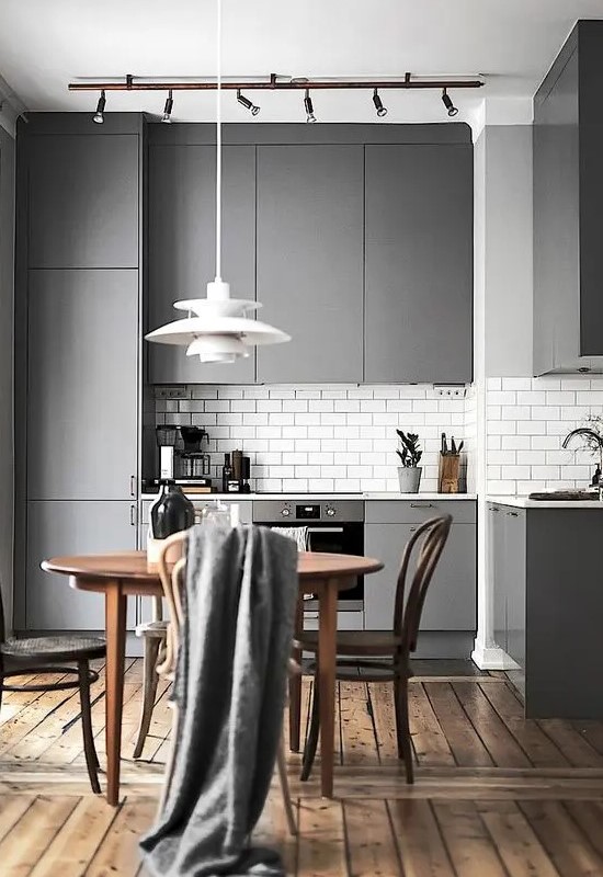a modern sleek grey kitchen with a white subway tile backsplash and a wooden floor for a cozy touch