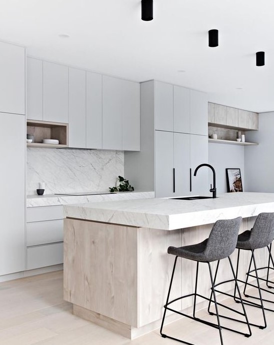 a neutral minimalist kitchen with dove grey cabinets, a white marble backsplash and countertops, a wooden kitchen island and felt stools