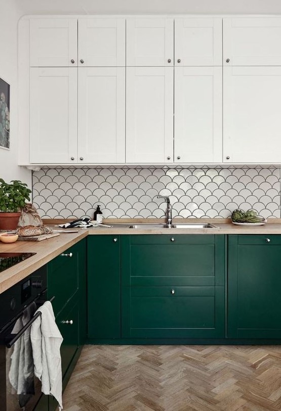 a refined kitchen with forest green and white cabinets, a fishscale tile backsplash and butcherblock countertops is cool