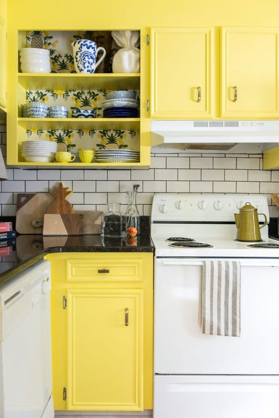 a retro kitchen done in white and yellow, with white appliances and a white subway tile backsplash plus black countertops