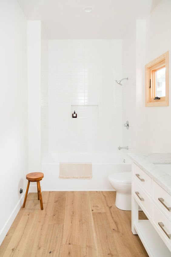 a serene white bathroom with white skinny and wood tiles, a vanity, a window, a tub and a wooden stool
