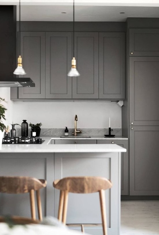 a simple contemporary space done in grey, with a white backsplash, stone countertops and metallic touches