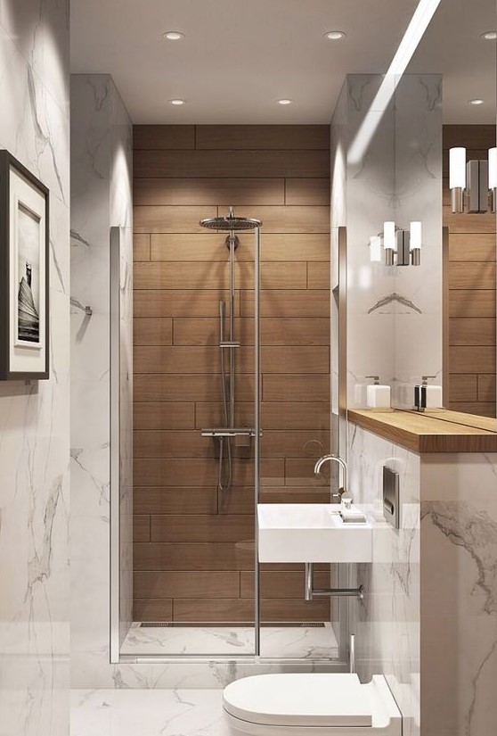 a small and refined bathroom clad with white stone tiles and with a wood tile accent in the shower, with white appliances and neutral fixtures