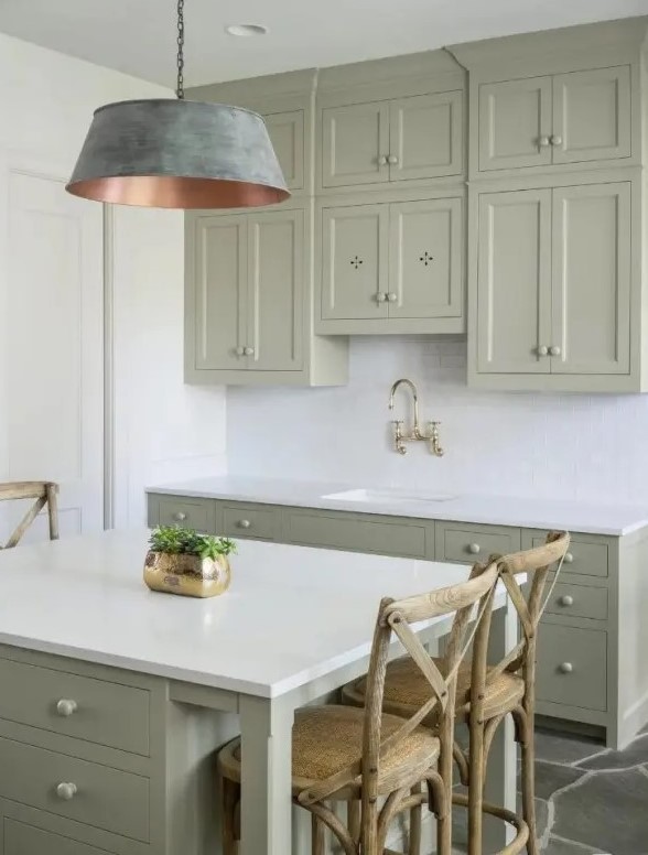 a small sage green kitchen with shaker and flat panel cabinets, a white subway tile backsplash and white countertops plus a catchy brushed lamp