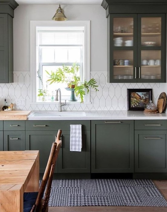 a stylish dark green kitchen with shaker cabinets, white countertops and a white tile backsplash plus retro lamps