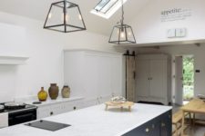 a stylish kitchen in white with a Victorian feel and a navy ktichen island, skylights and pendant lamps highlight the space