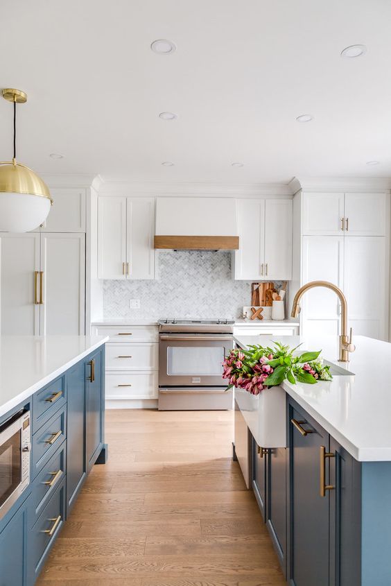 a stylish kitchen with blue kitchen islands, white cabinets and countertops plus chic brass touches