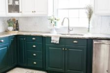 a stylish kitchen with dark green and white cabinets, stone countertops and touches of metallics here and there