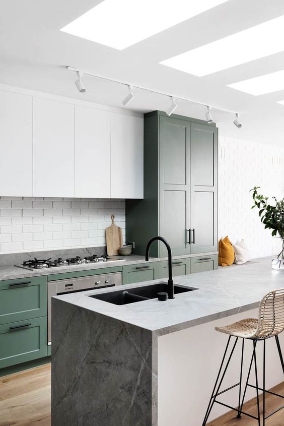 a stylish modern kitchen with green and white cabinets, a white brick backsplash and grey stone countertops is ultimate