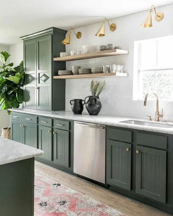 a stylish olive green farmhouse kitchen with fluted cabinets, white stone countertops, open shelves, brass and gold lamps