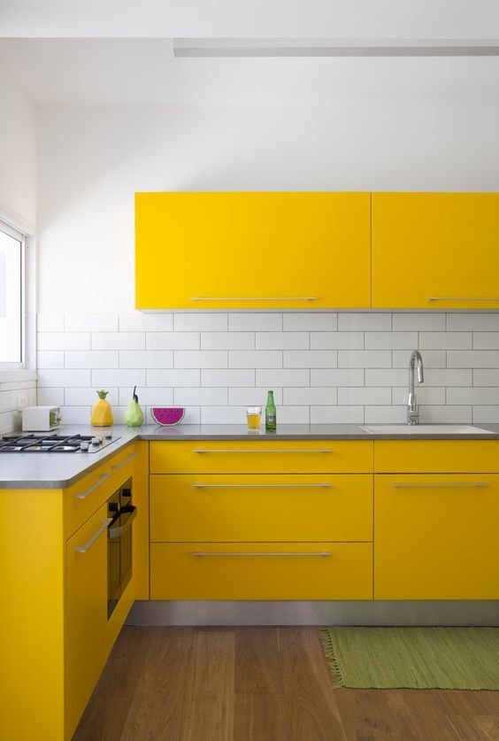 a super bright contemporary kitchen with yellow cabinets, a white subway tile backsplash and a wooden floor looks wow
